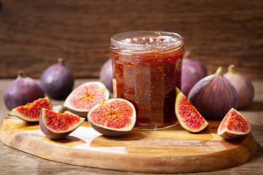 Jam in jar surrounded by figs on table